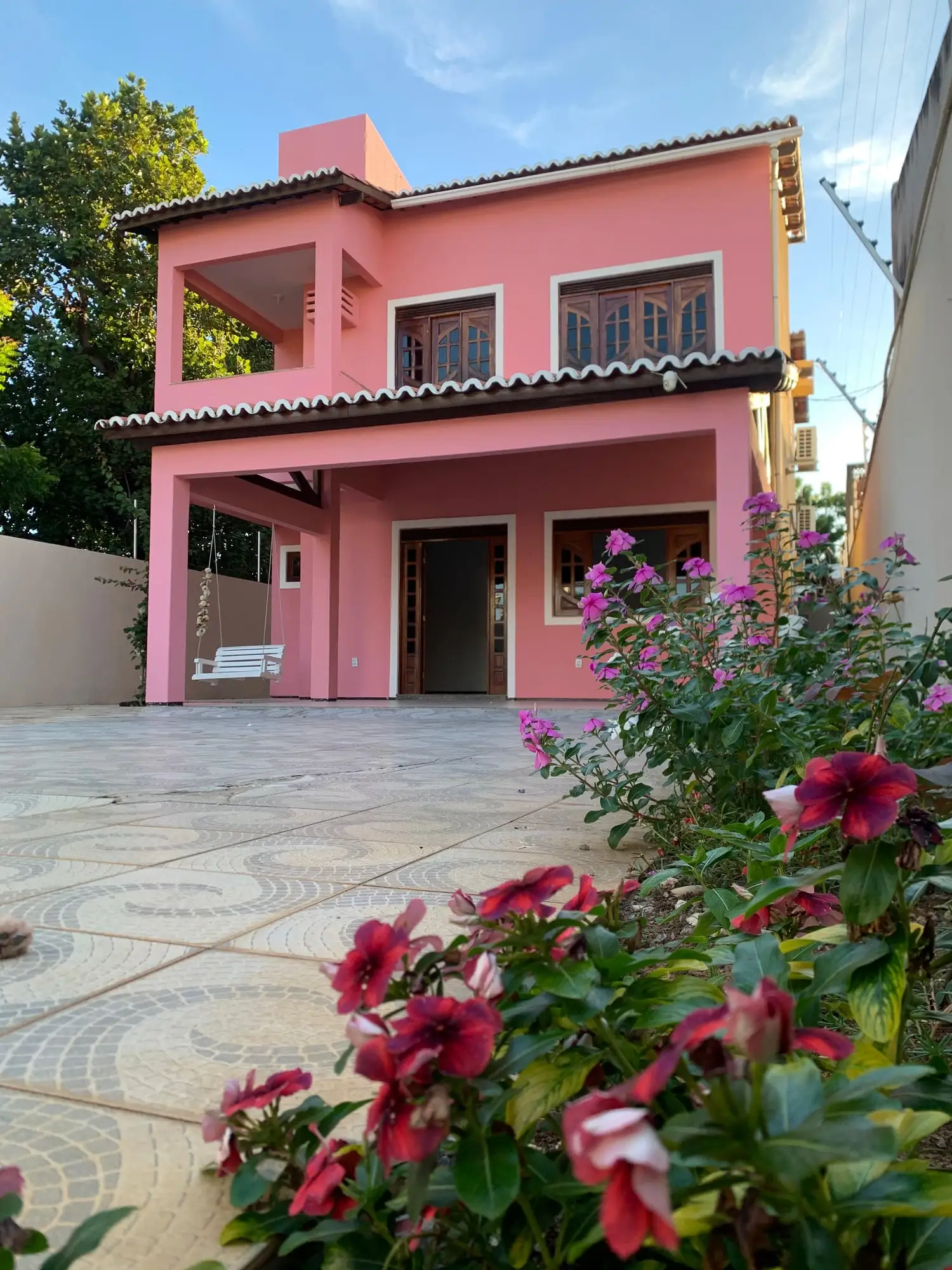 Fachada rosa do estúdio, com jardim de flores na frente